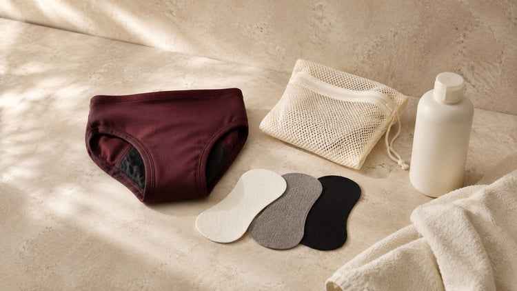 Folded period-style underwear with abstract absorbent fabric layers and gentle washing accessories.