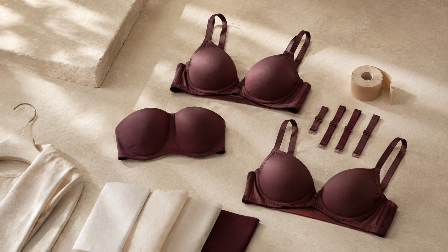 T-shirt, strapless and convertible bras with breast tape and outfit-fabric swatches in a premium flat-lay.